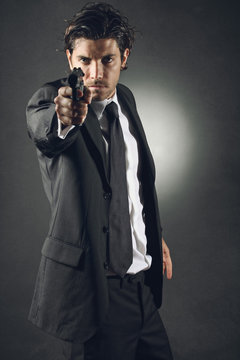 Handsome bodyguard aiming with gun