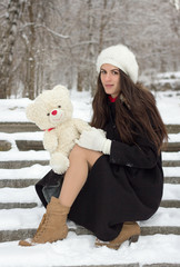 Cheerful Caucasian Young Woman in Snowy Weather holds a toy