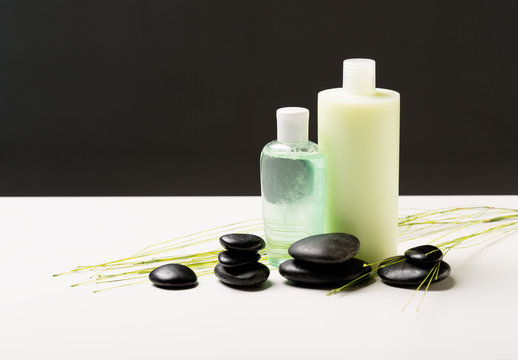 shampoo bottle, massage stones and green plant