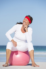 Happy sporty mature woman beach exercising