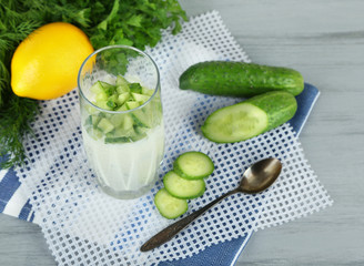 Cucumber yogurt in glass, on color napkin, on wooden