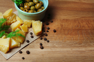 Parmesan cheese, fresh herbs and olives on wooden background