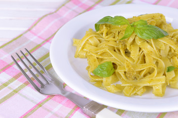 Delicious pasta with pesto on plate on table close-up