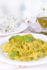 Delicious pasta with pesto on plate on table on light
