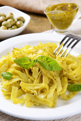 Delicious pasta with pesto on plate on table close-up