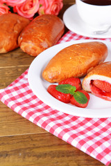 Fresh baked pasties with strawberries on plate on table