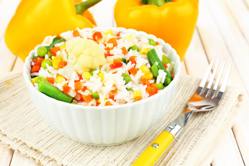 Cooked rice with vegetables on wooden table close up