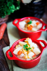 Chicken noodle soup with vegetables in red bowl on rustic table