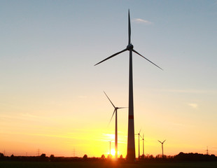 Fototapeta na wymiar Windmills standing in the field at sunset time