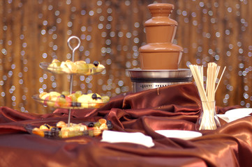 Chocolate fountain on the silk tablecloth in restaurant