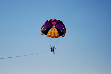 Two girls enjoying parasailing in blue sky