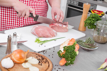 Frau in der Küche schneidet Schweinefleisch