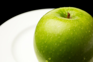 A fresh green apple on a black background