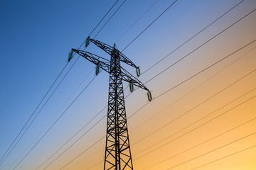 Electric power lines against blue and yellow sky - 60928232