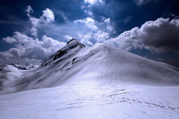 Snowy  and shiny mountain top with footsteps in the foreground