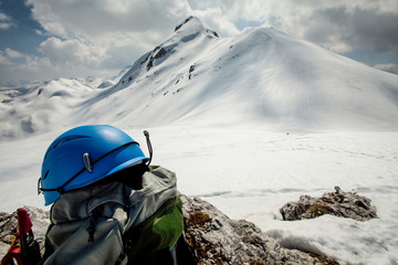 Helmet and backpack on a rock with white mountain in background