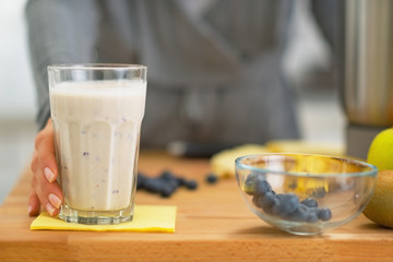 Young woman taking smoothie from table