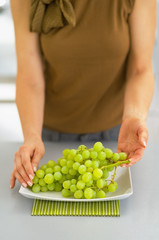 Closeup on young woman with branch of grapes