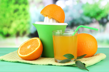 Citrus press, glass of juice and ripe oranges