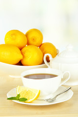 Obraz na płótnie Canvas Cup of tea with lemon on table on light background