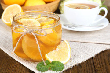 Tasty lemon jam with cup of tea on table close-up