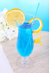 Glass of cocktail on table on light blue background
