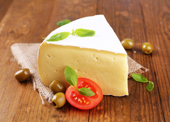 Tasty Camembert cheese with tomato, basil and olives,