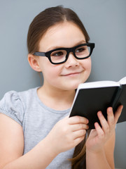 Fototapeta premium Little girl is reading a book