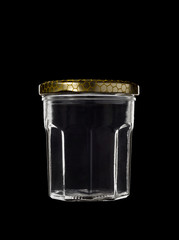 Transparent glass jar on black background, with the closed gold color top