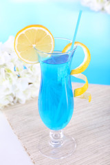 Glass of cocktail on table on light blue background