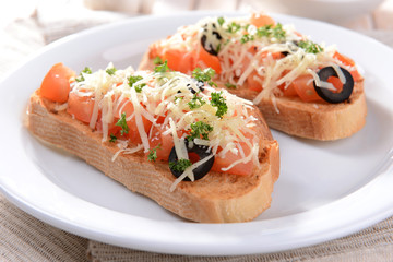 Delicious bruschetta with tomatoes on plate on table close-up
