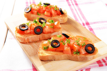 Delicious bruschetta with tomatoes on cutting board close-up