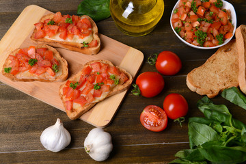 Delicious bruschetta with tomatoes on cutting board close-up