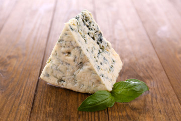 Tasty blue cheese with basil, on wooden table