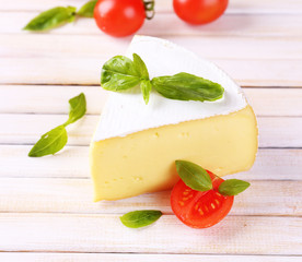 Tasty Camembert cheese with basil and tomatoes, on wooden table