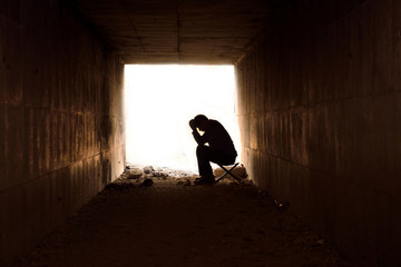depressed man sitting in the tunnel - obrazy, fototapety, plakaty