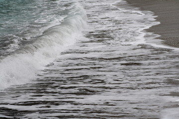 white waves crashing on sand beach