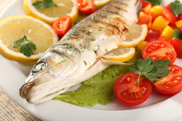 Delicious grilled fish on plate on table close-up