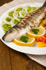 Delicious grilled fish on plate on table close-up