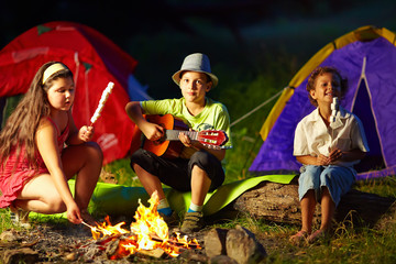 happy teens around night campfire