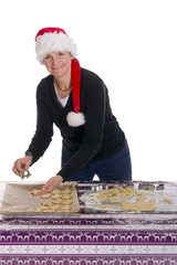 Frau mit Weihnachtsmannmütze backt Plätzchen