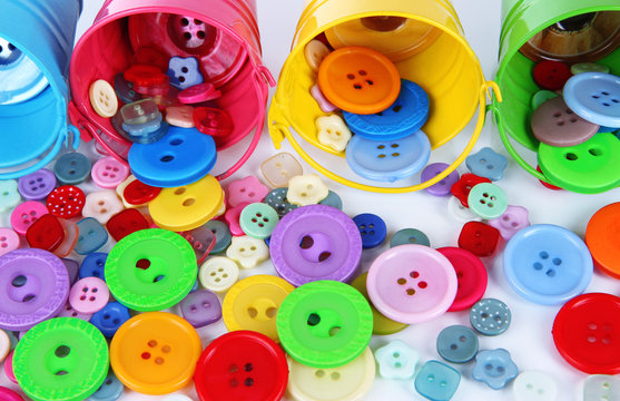 Colorful buttons strewn from buckets close-up