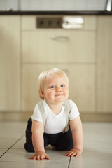 Little boy sitting on the floor and smiling.