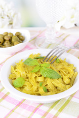 Delicious pasta with pesto on plate on table on light