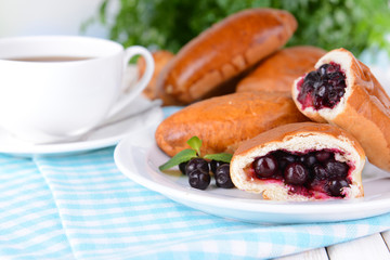 Fresh baked pasties with currant on plate on table close-up