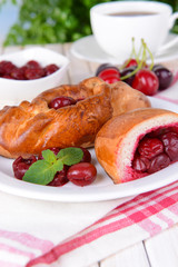 Fresh baked pasties with cherry on plate on table close-up