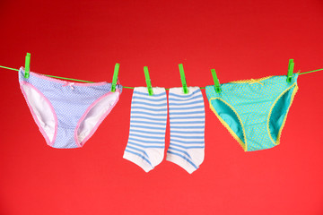 Baby clothes hanging on clothesline, on color background