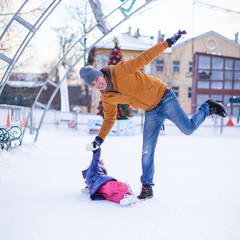 Young funny father and adorable little girl on a skating rink
