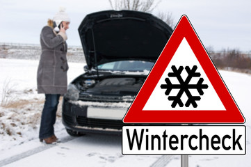 Schild Wintercheck und Frau mit kaputtem Auto