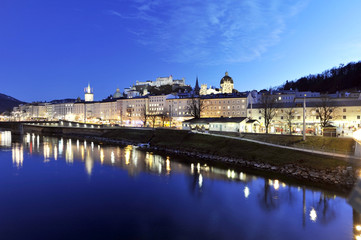 The night view on old Salzburg with medieval edifices in Altstadt district and fast flowing Salzach river, Austria